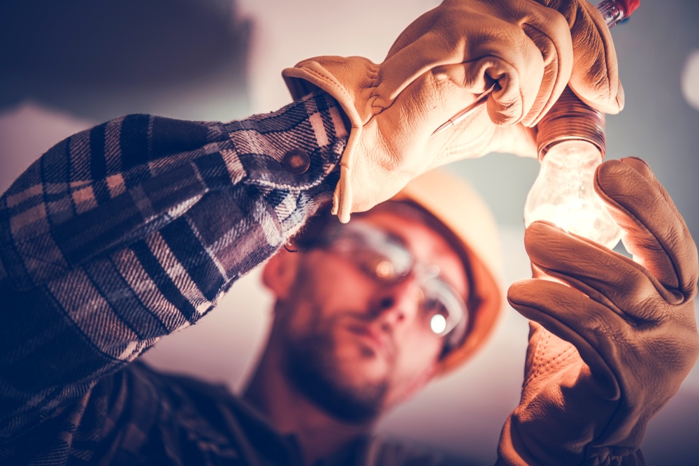 Electrician fixing a bulb with safety gloves